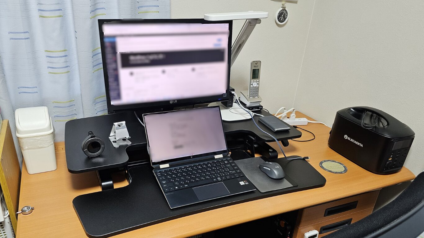 サンワダイレクト卓上スタンディングデスク100-MR205BKの座位モード。23インチモニターとノートPCのデュアルモニタ構成で快適なデスクワーク環境を実現