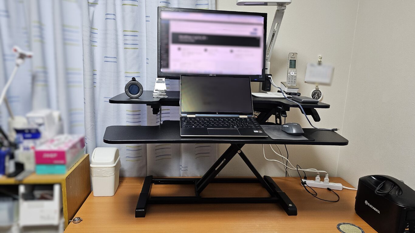 サンワダイレクト卓上スタンディングデスク100-MR205BKの立位モード。油圧式で簡単に高さ調整し、立ったまま作業できる環境。集中力向上と座りすぎ防止に効果的